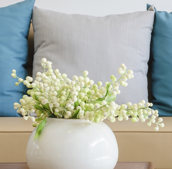 plant in ceramic vase on wooden table with modern sofa at home